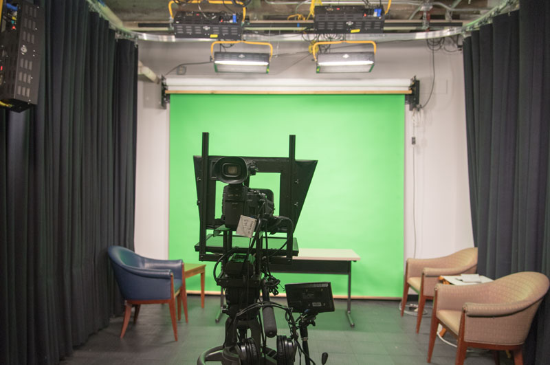 Small room holding green screen and video camera on dolly