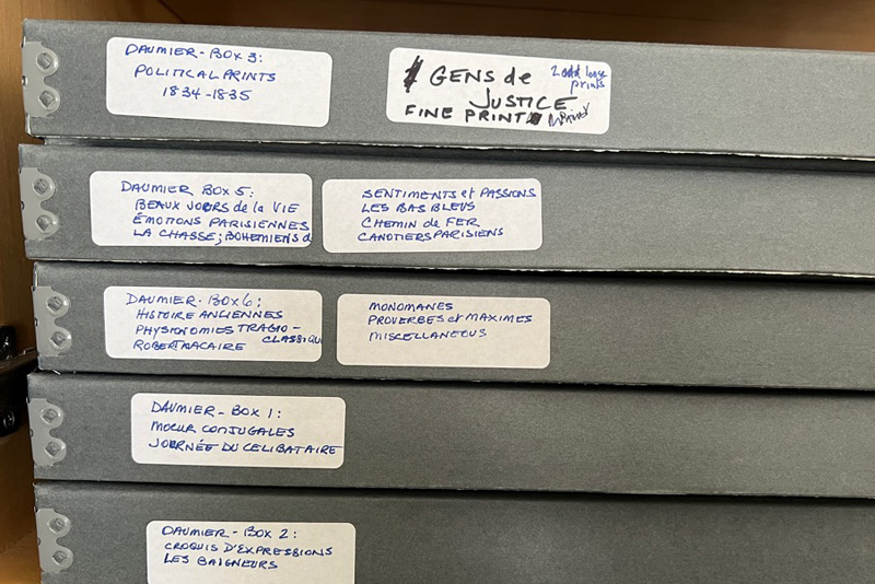 A stack of 5 gray boxes, with labels affixed to them revealing that they contain materials by the French artist Honoré Daumier.