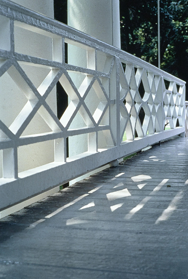 Criss-cross handrail pattern of white painted wood, outdoors.
