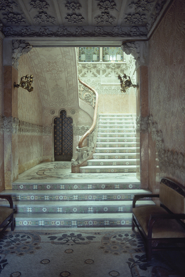 A stairway with elegant style and a curving handrail. Sunlight filters from above.